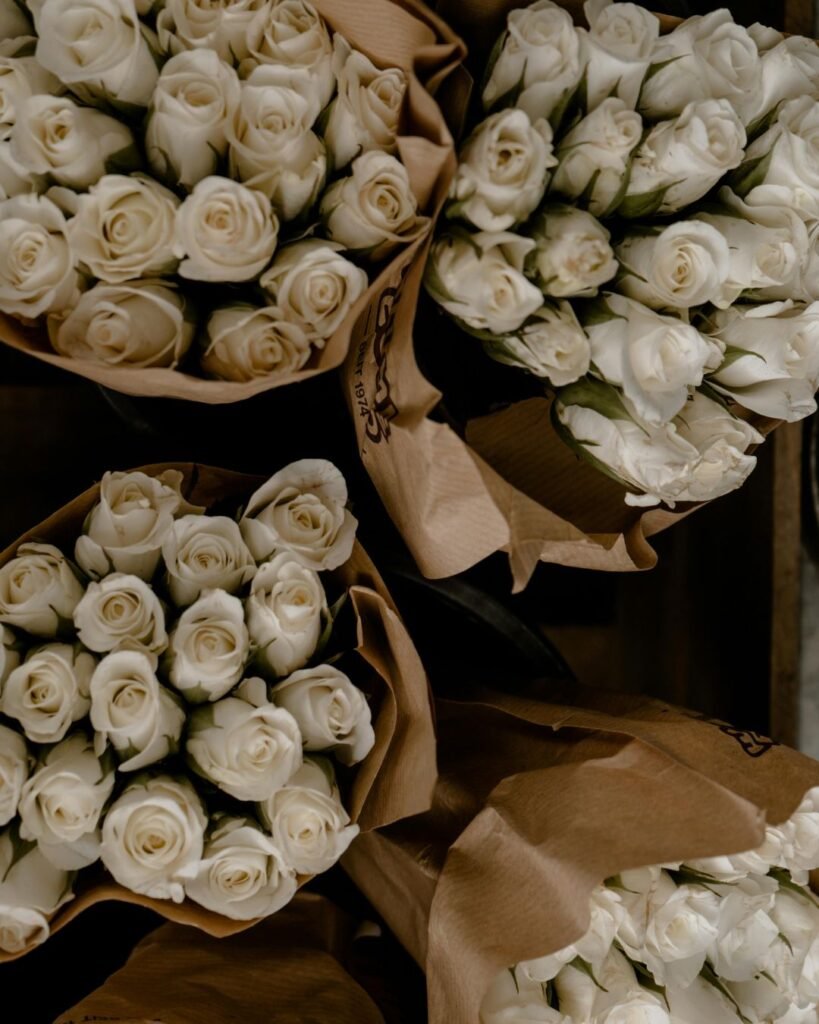 Bouquets of white roses wrapped in brown kraft paper, displayed from a top-down view.

