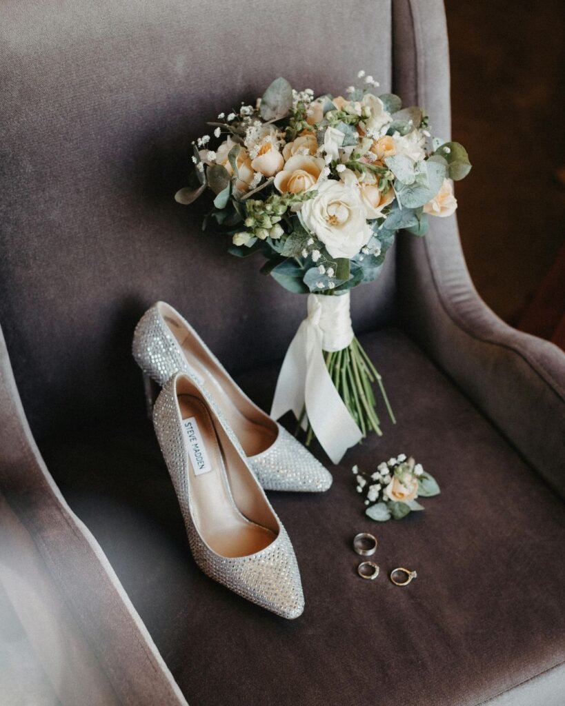 Bridal heels, bouquet, and wedding rings arranged on a chair during wedding prep timeline