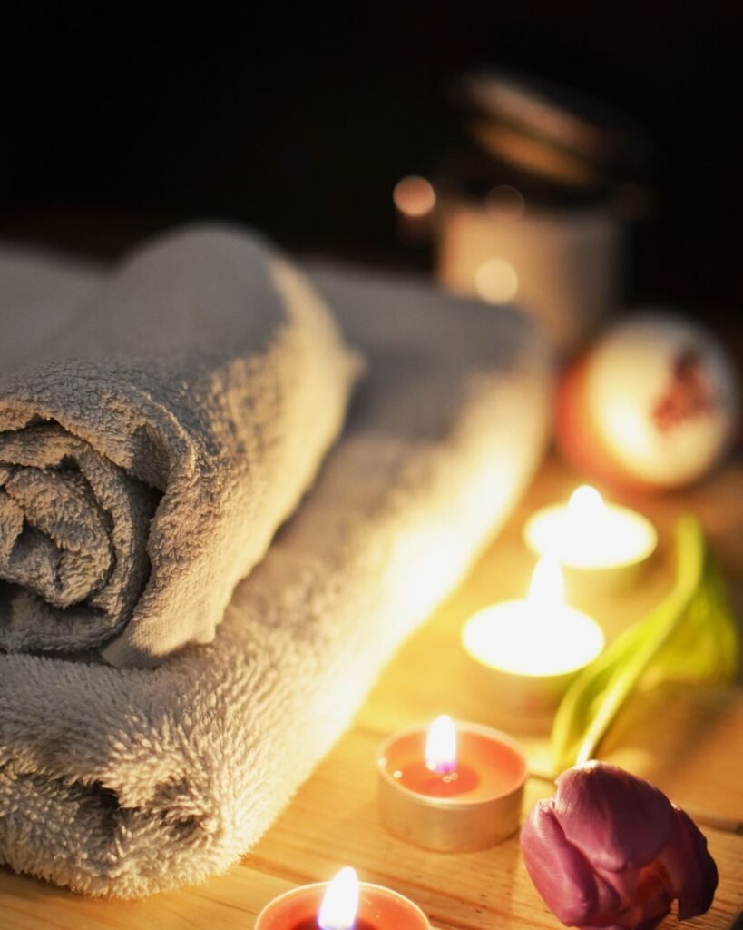 Rolled spa towels with tealight candles and a purple tulip – relaxing setup for a mini spa night at home