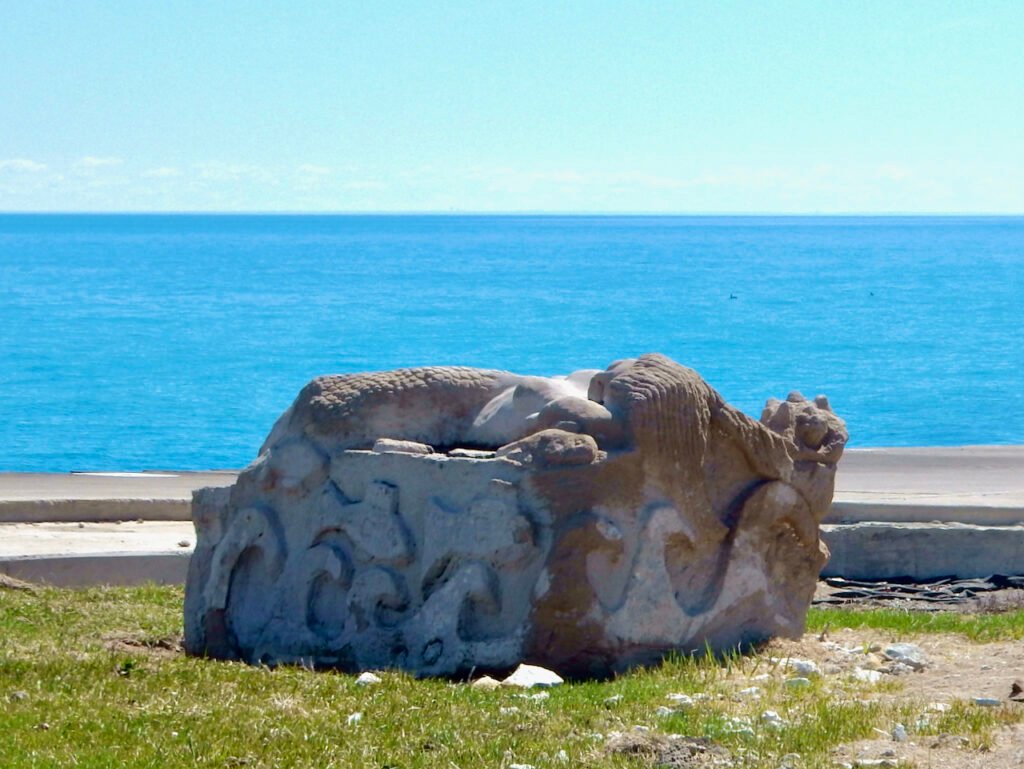 "Wide shot of the Secret Mermaid Chicago lounging beside Lake Michigan, framed by bright blue water and open sky.