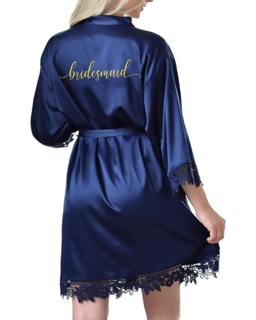 “Back view of a personalized bridal robe in navy satin with gold “bridesmaid” embroidery and lace trim on the sleeves and hem.