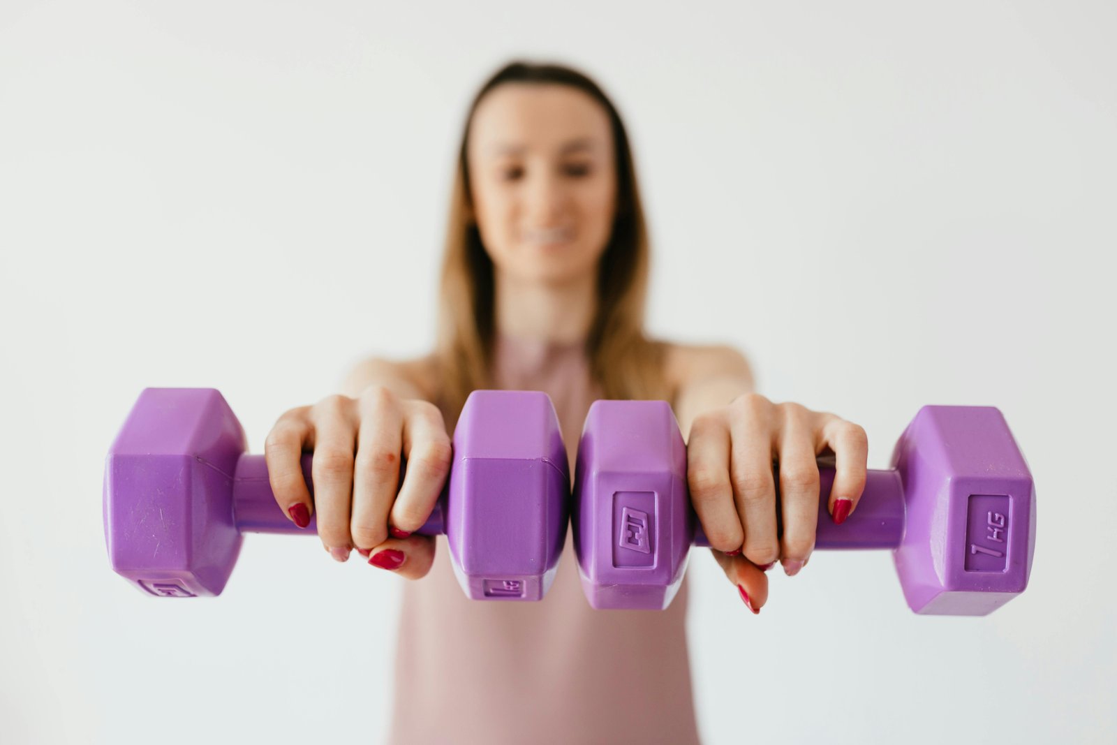 Woman holding purple dumbbells while working out at home