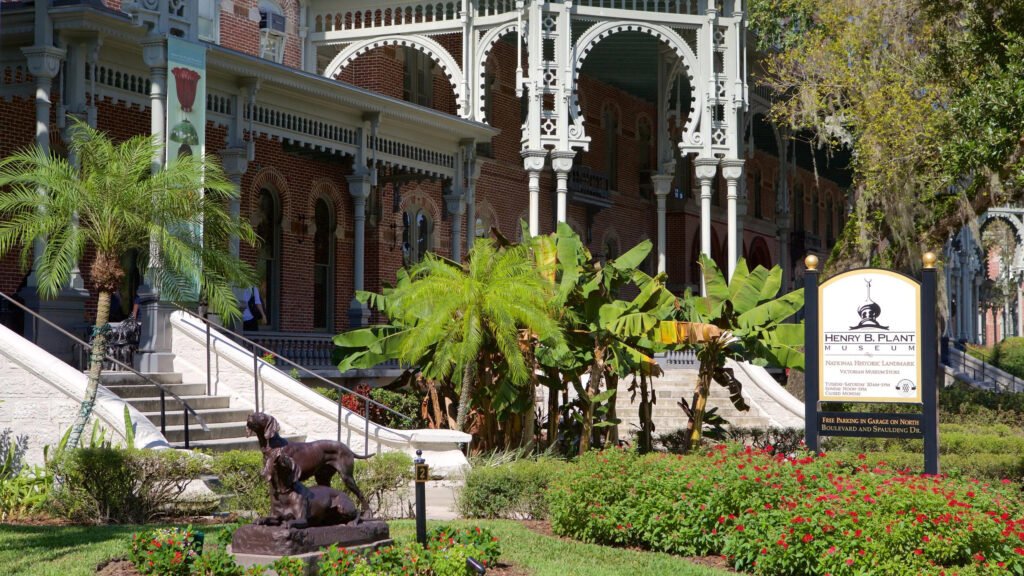 Entrance of the Henry B. Plant Museum in Tampa with Victorian architecture, palm trees, and historic statues.