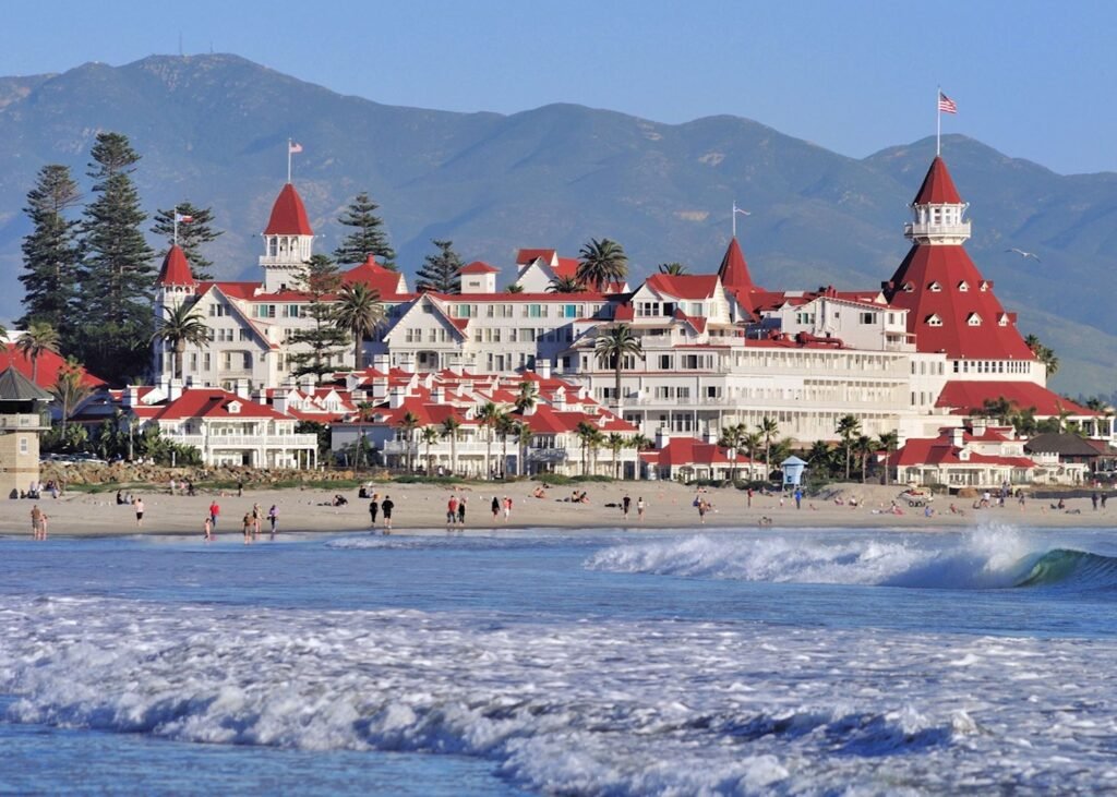 Beachfront view of Hotel del Coronado in San Diego, California with waves and visitors on the sand