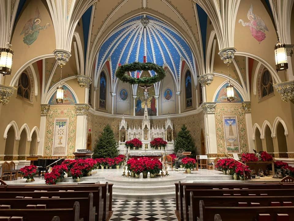 Interior of St. Andrew’s Catholic Church Pasadena with colorful murals, altar, poinsettias, and Christmas decorations.