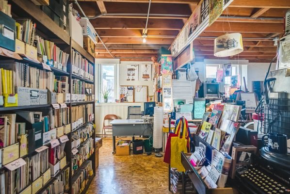 Interior of the Denver Zine Library with shelves full of zines, posters, and a cozy reading area.