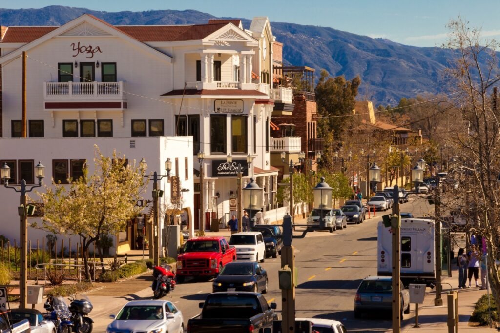 View of Old Town Temecula with shops, cars, and mountain backdrop on a sunny day.