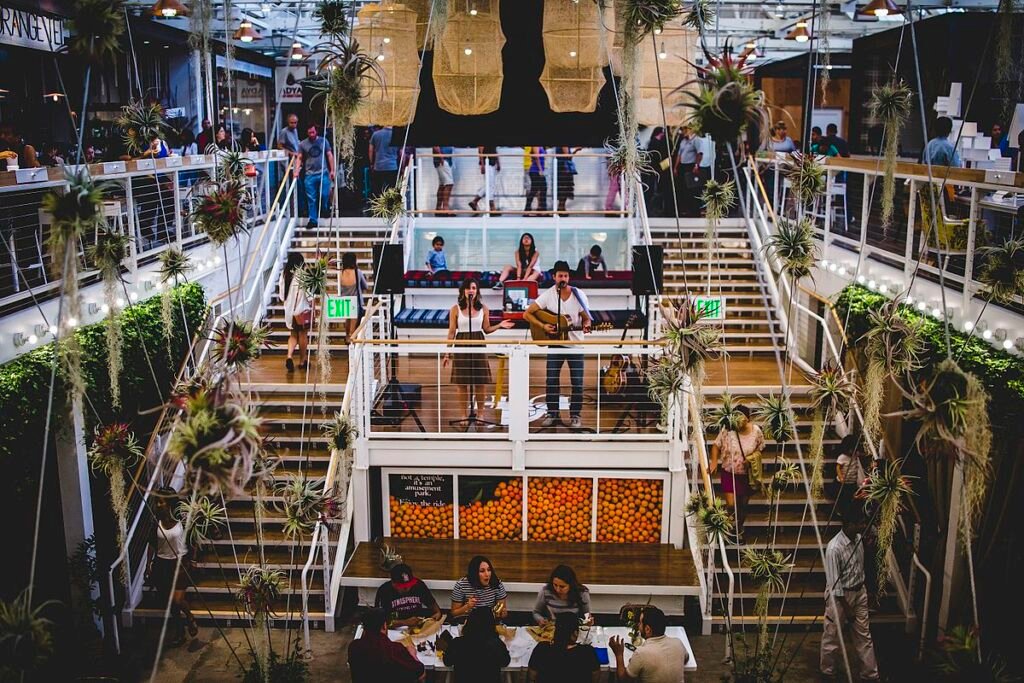 Inside the Anaheim Packing House food hall filled with people, lights, and live music in Orange County.