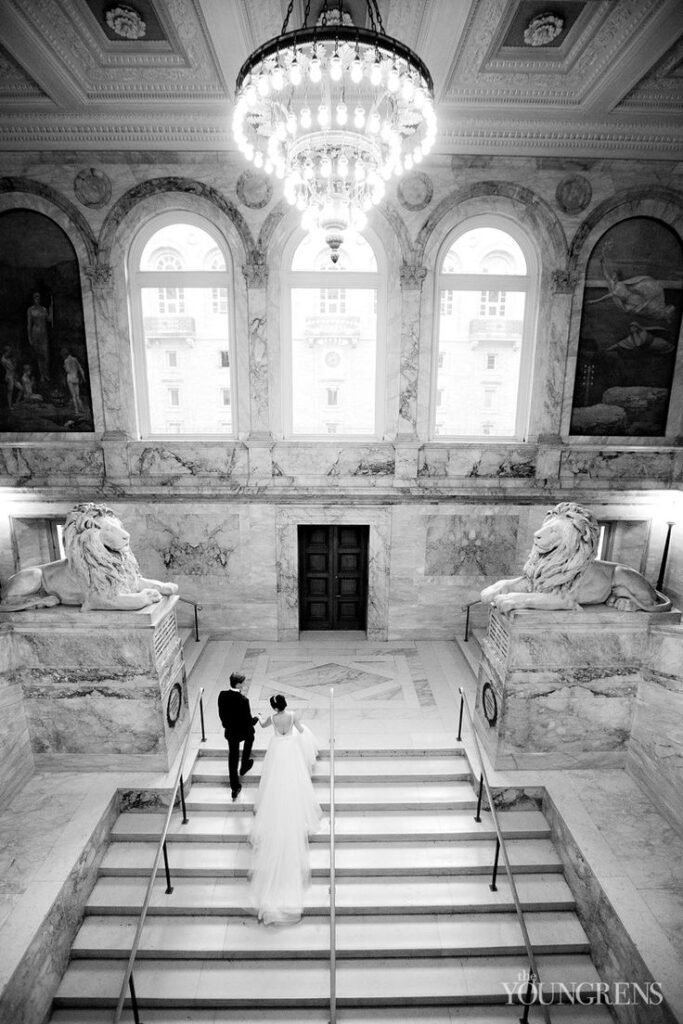 Bride and groom walking up marble staircase inside Boston Public Library wedding venue.