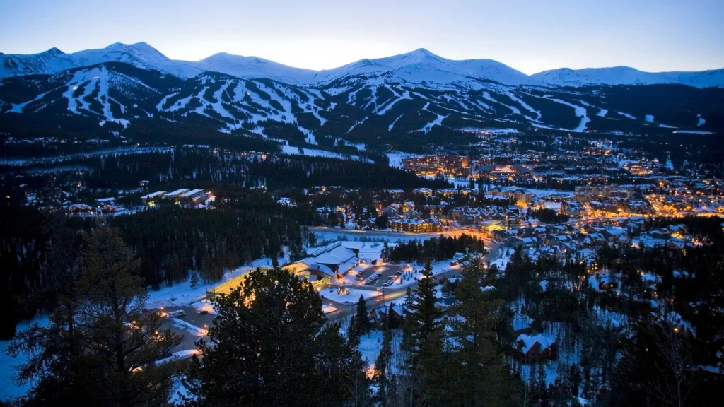 Breckenridge mountain town lit up at dusk with snow-covered ski slopes in Summit County, Colorado.