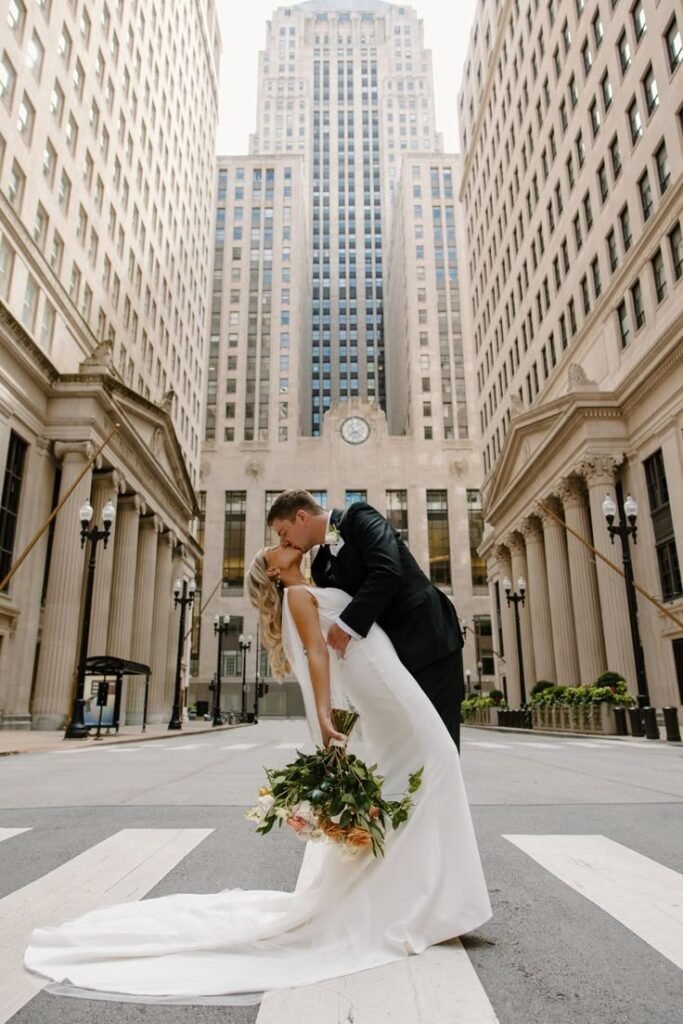 Bride and groom sharing a romantic dip kiss in front of tall city buildings during a Boston wedding photoshoot.