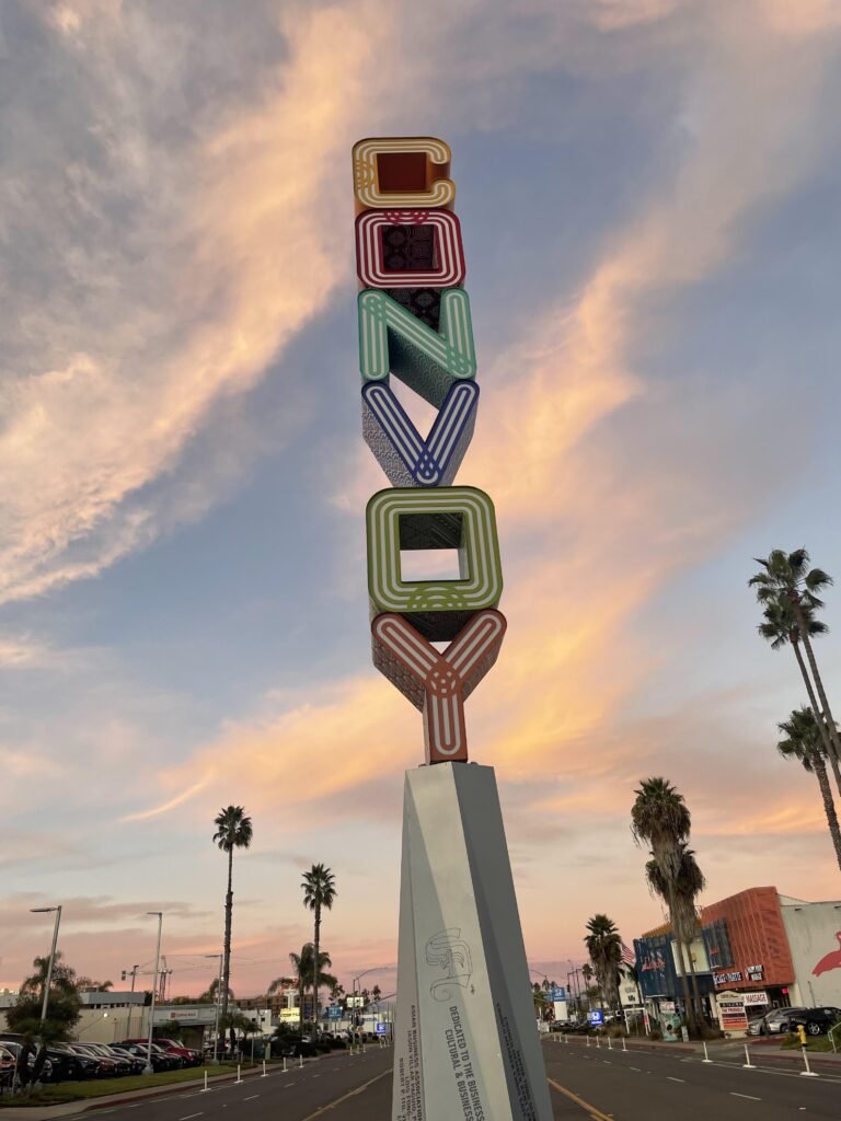 The Convoy District monument sign in San Diego, surrounded by palm trees and Asian restaurants.