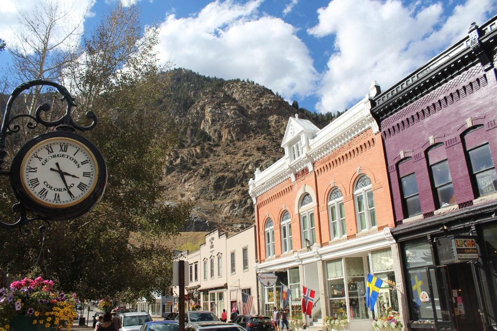 Historic downtown Georgetown, Colorado with clock tower and colorful buildings against mountain backdrop.