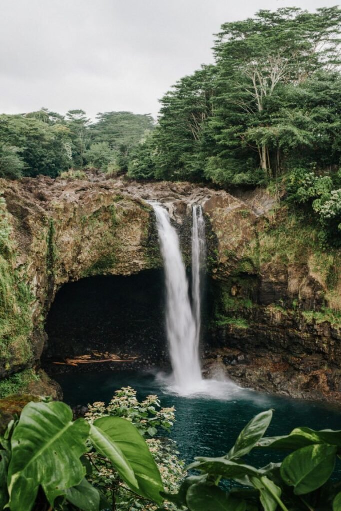 Scenic waterfall near Kona Village Resort on the Big Island, surrounded by tropical rainforest and lava cliffs.