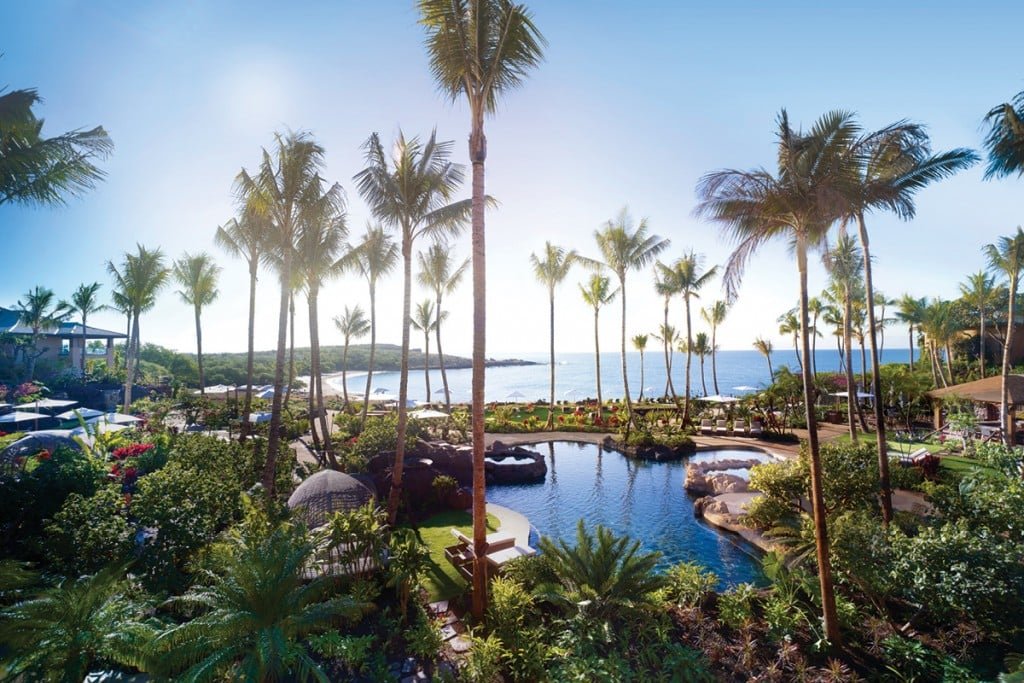 Palm trees and lagoon-style pool with ocean view at a resort on Lānaʻi, Hawaii.