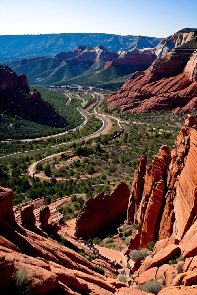 Aerial view of Red Rocks Amphitheatre and winding mountain roads near Denver, Colorado, showcasing red sandstone formations under clear skies.