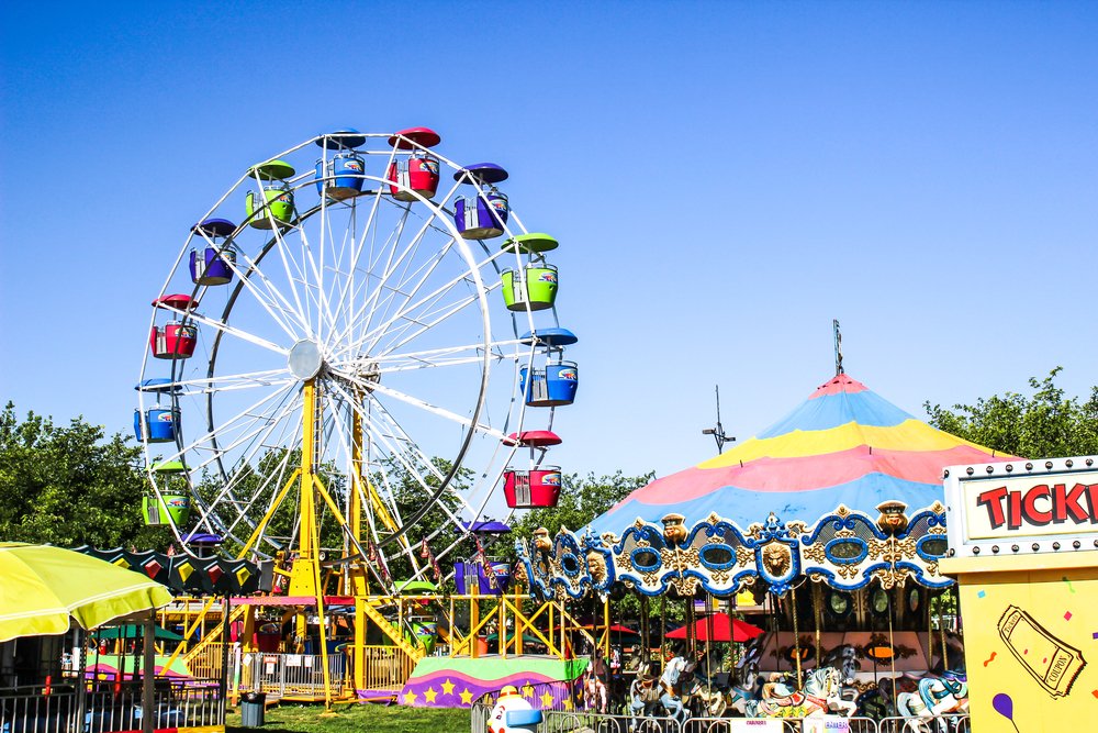 Bright Ferris wheel and carousel at a local fairground in Orange County during the weekend.