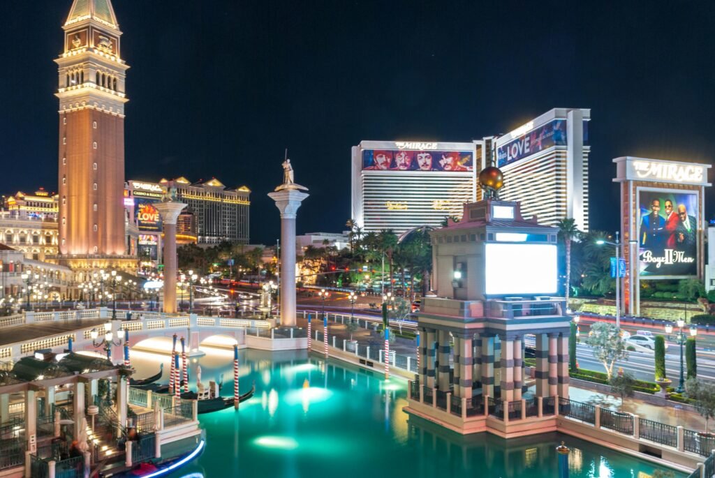 Night view of The Venetian and The Mirage hotels on the Las Vegas Strip with glowing water reflections.