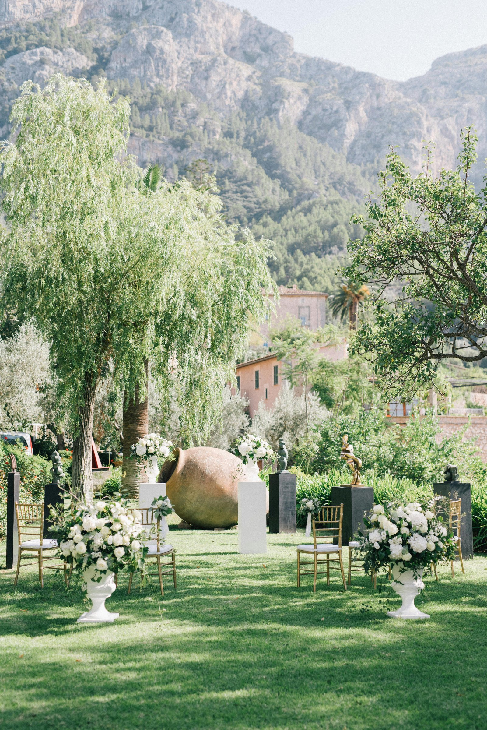 Outdoor garden ceremony setup for wedding planning in Hawaii with floral décor, gold chairs, and mountain scenery.