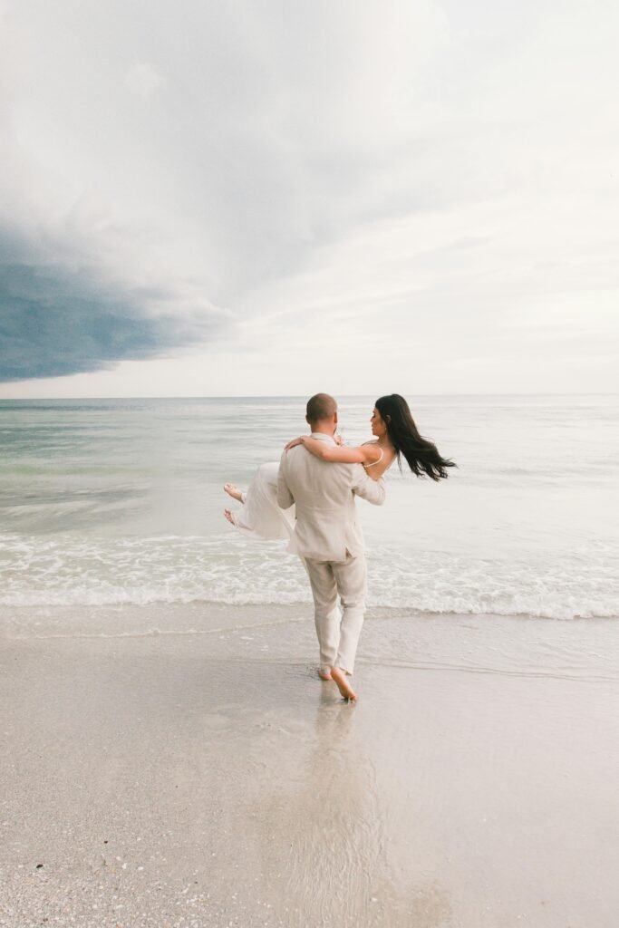 Groom carrying bride along the shoreline during a destination wedding in Florida on a budget