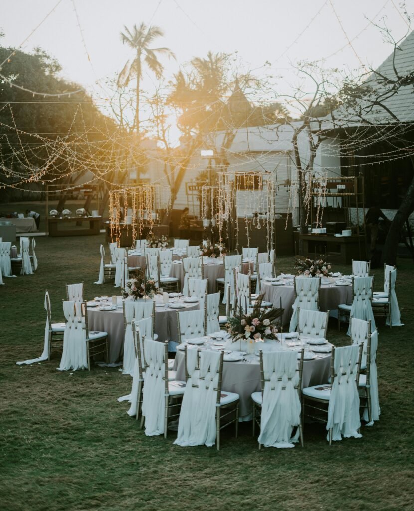Outdoor reception setup for desert elopement wedding ideas with round tables, white chairs, and string lights at sunset.