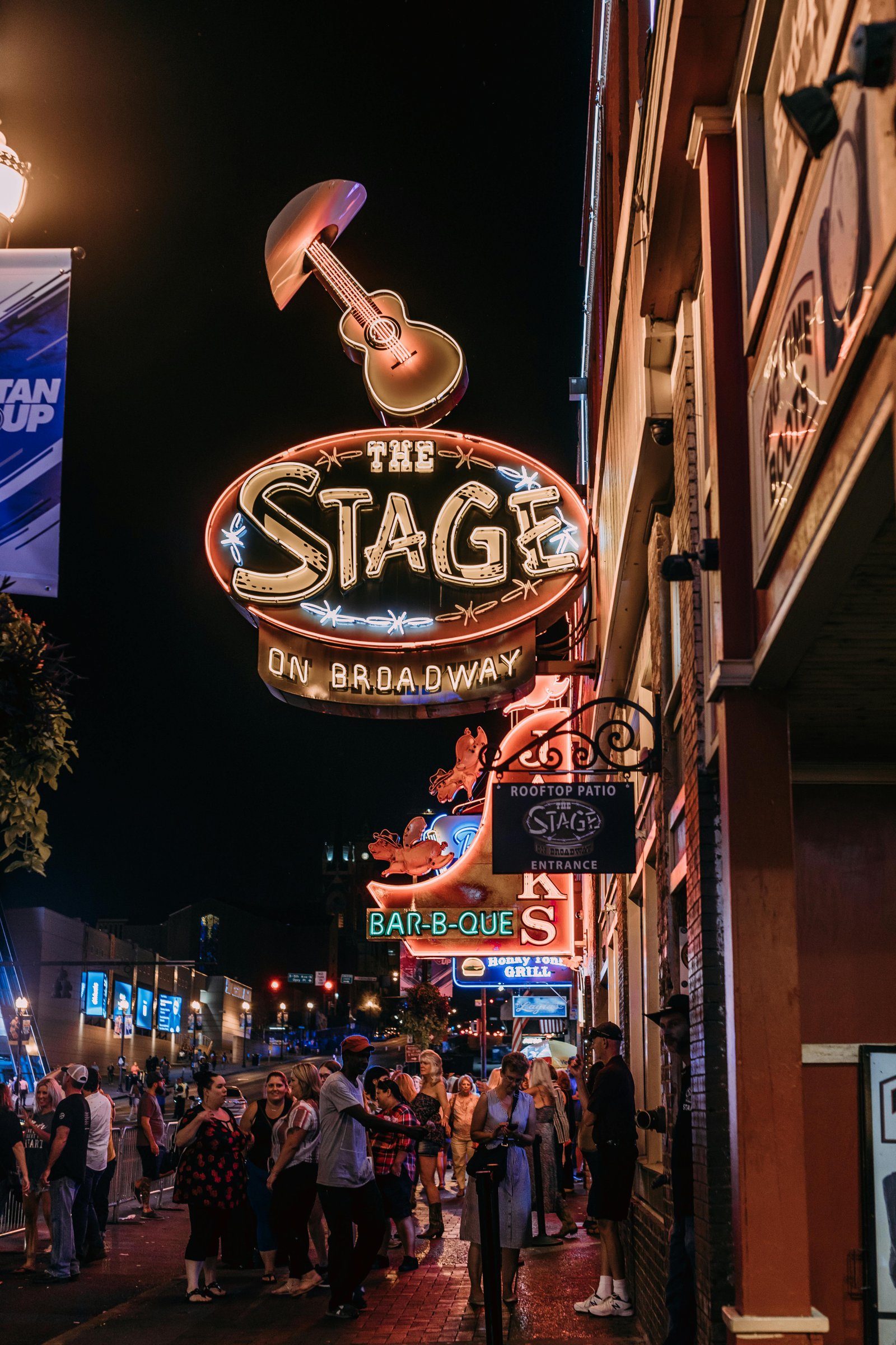 Neon signs and crowd outside The Stage on Broadway in Nashville at night