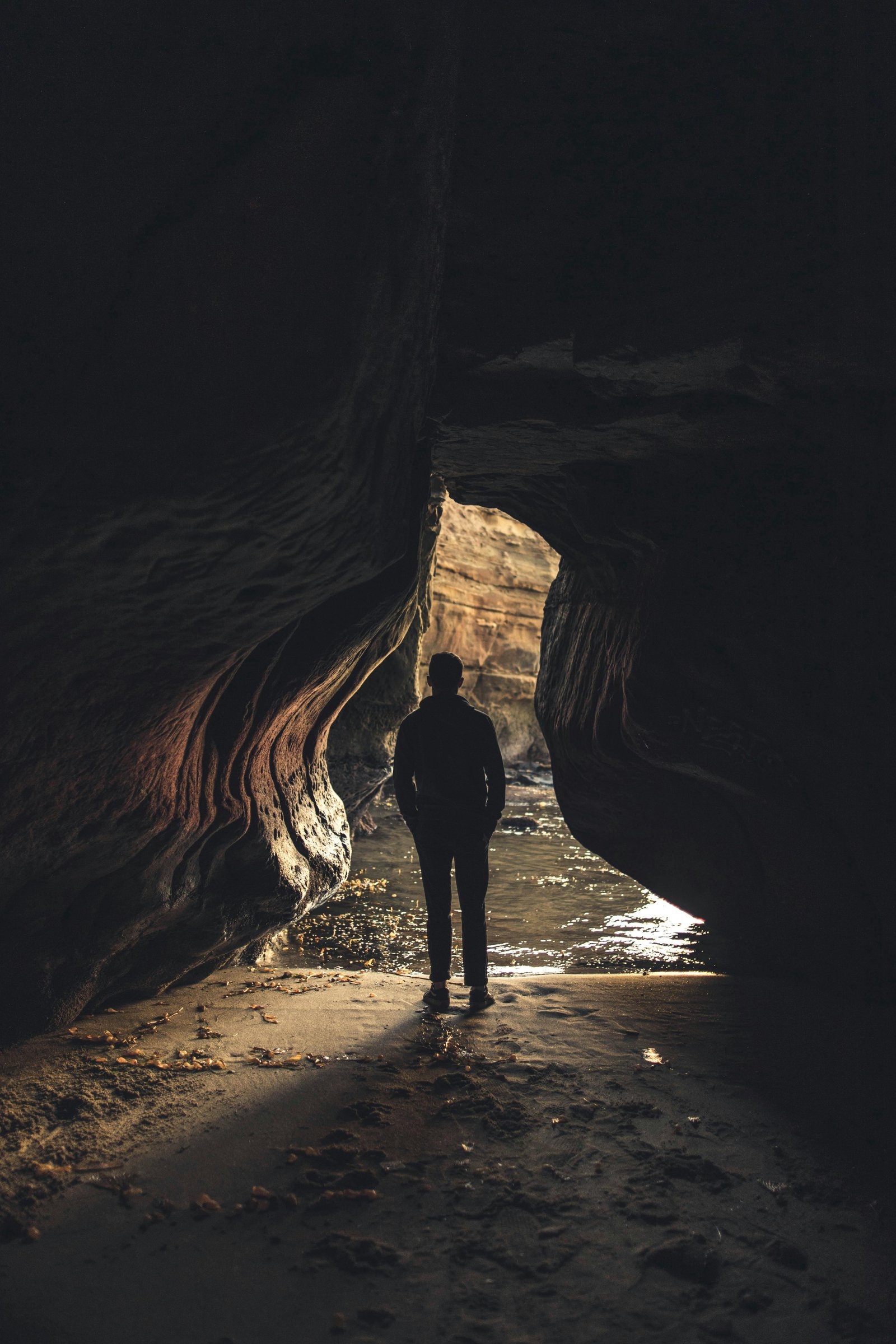 Person standing inside a sea cave at Sunset Cliffs during a coastal hike in San Diego
