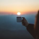 person showing white mug in focus photography