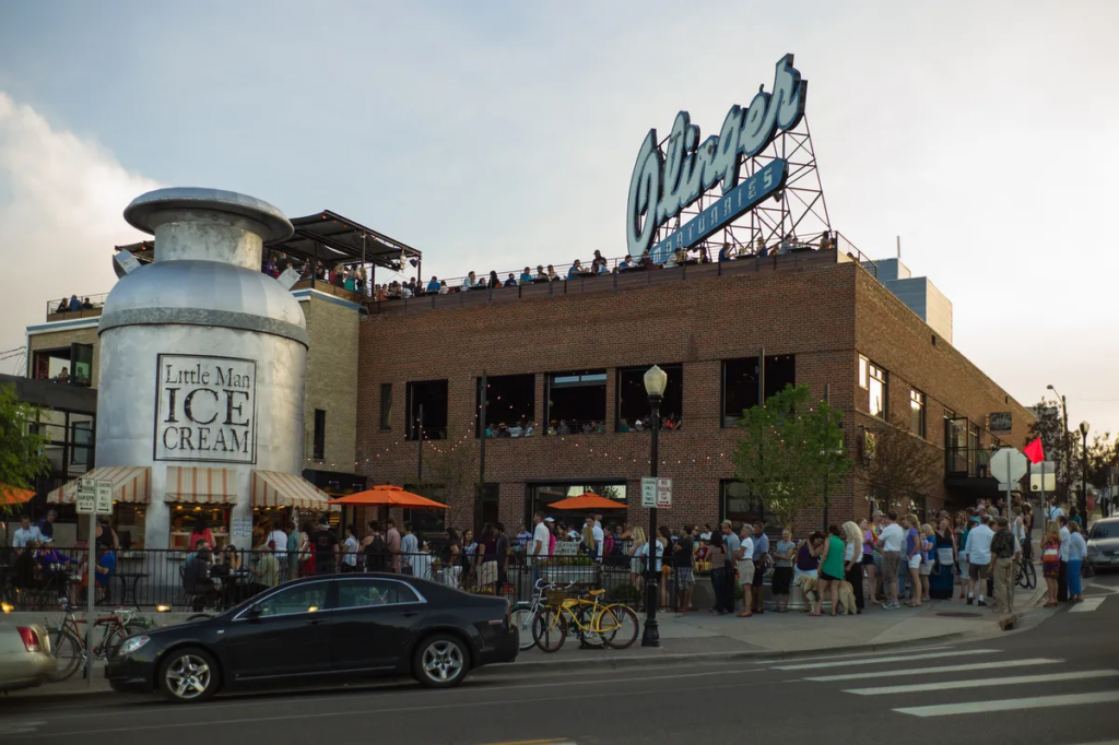 Exterior view of Linger Eatuary in Denver with rooftop diners and the historic Olinger Mortuaries sign