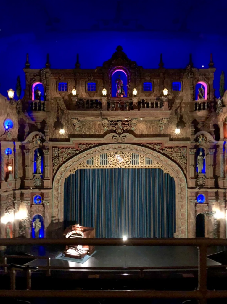 Ornate interior of Tampa Theatre in Tampa Florida featuring a grand stage, vintage Wurlitzer organ, and Mediterranean Revival-style architecture.