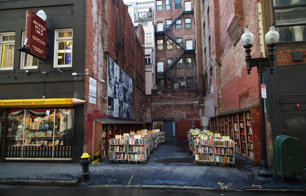 Outdoor book lot at Brattle Book Shop in Boston, surrounded by historic brick buildings and filled with carts of secondhand books.