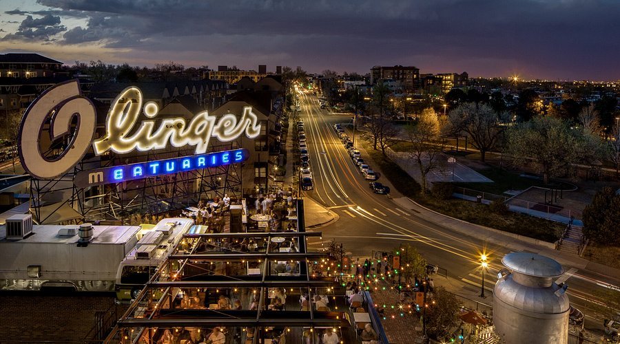 Night view from Linger Eatuary’s rooftop showing Olinger sign and Denver skyline