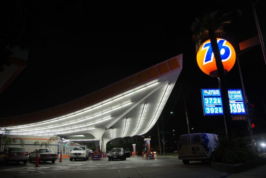 Union 76 Gas Station Beverly Hills illuminated at night; glowing orange “76” globe sign and dramatic canopy lighting