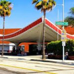Iconic Union 76 Gas Station in Beverly Hills with its swooping mid-century canopy framed by palm trees on a sunny day