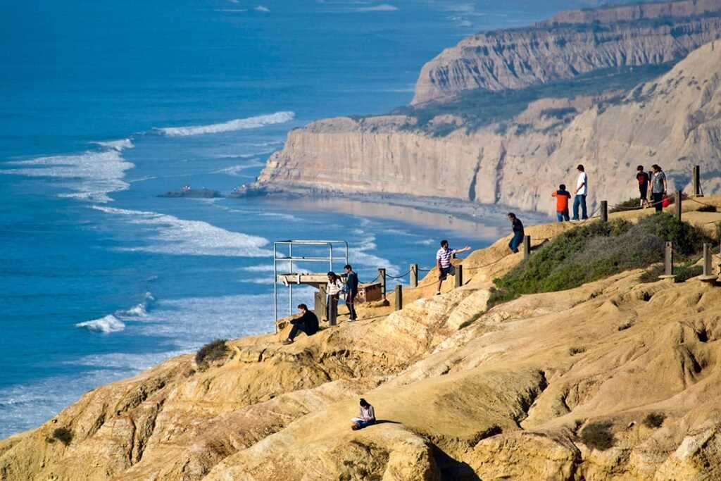 Visitors hike along a sandstone ridge above waves and Black’s Beach at Torrey Pines State Natural Reserve, La Jolla.