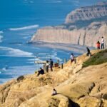 Visitors hike along a sandstone ridge above waves and Black’s Beach at Torrey Pines State Natural Reserve, La Jolla.