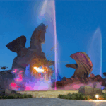 Pegasus and Dragon statue in Hallandale Beach glowing with colorful fountain lights at night