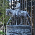 John Wayne Statue in Beverly Hills, full side view of the bronze cowboy on horseback outside a glass office building