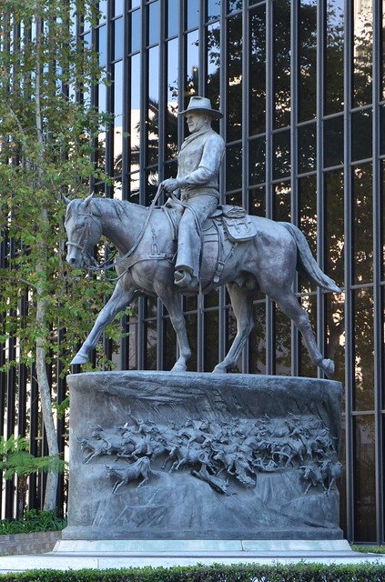 John Wayne Statue in Beverly Hills, full side view of the bronze cowboy on horseback outside a glass office building