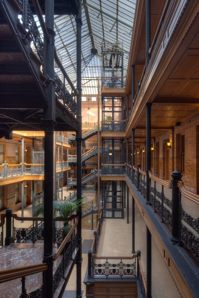 Wide interior view of Bradbury Building Los Angeles showcasing ornate iron balconies, central elevator shaft, and skylit ceiling