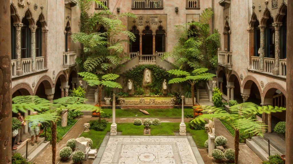 Wide view of Gardner Museum Boston courtyard featuring lush ferns, arched loggias, and a mosaic floor