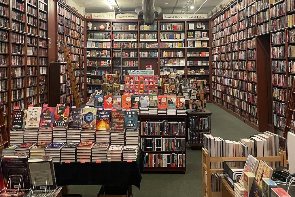 Interior of Mysterious Bookshop New York: floor-to-ceiling mystery shelves and a central table stacked with new thrillers