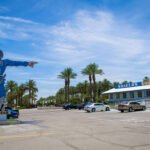 Iconic knight sign pointing toward Shields Date Garden Indio on Highway 111, with palm trees and a bright desert sky