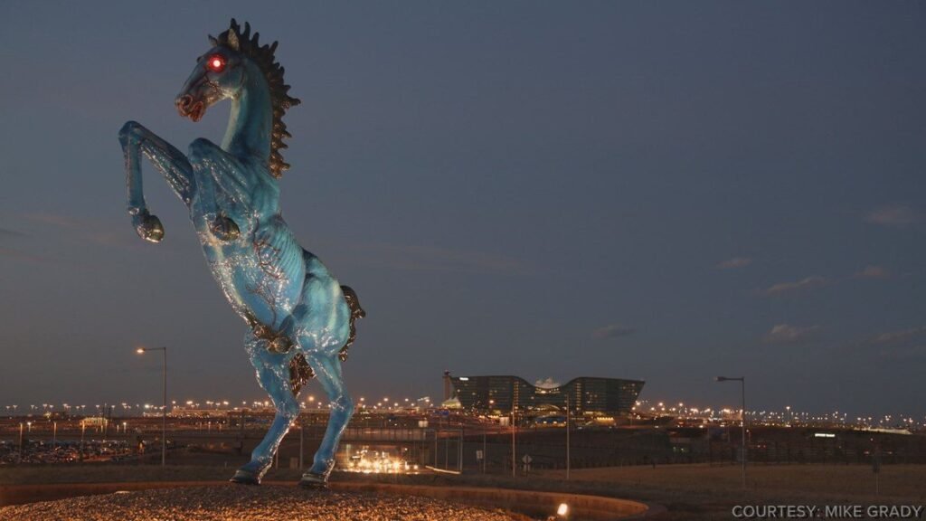 Blue Mustang Denver at night with glowing red eyes overlooking Denver International Airport