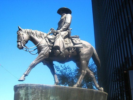 Low-angle photo of the John Wayne Statue in Beverly Hills against a bright blue sky