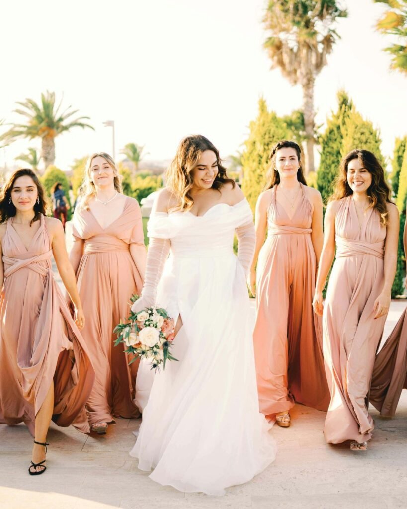 Bride with bridesmaids in neutral-toned dresses walking outdoors, styled for a neutral wedding dress code