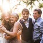 Bride and groom smiling with parents at golden hour before surprise wedding dance with parents