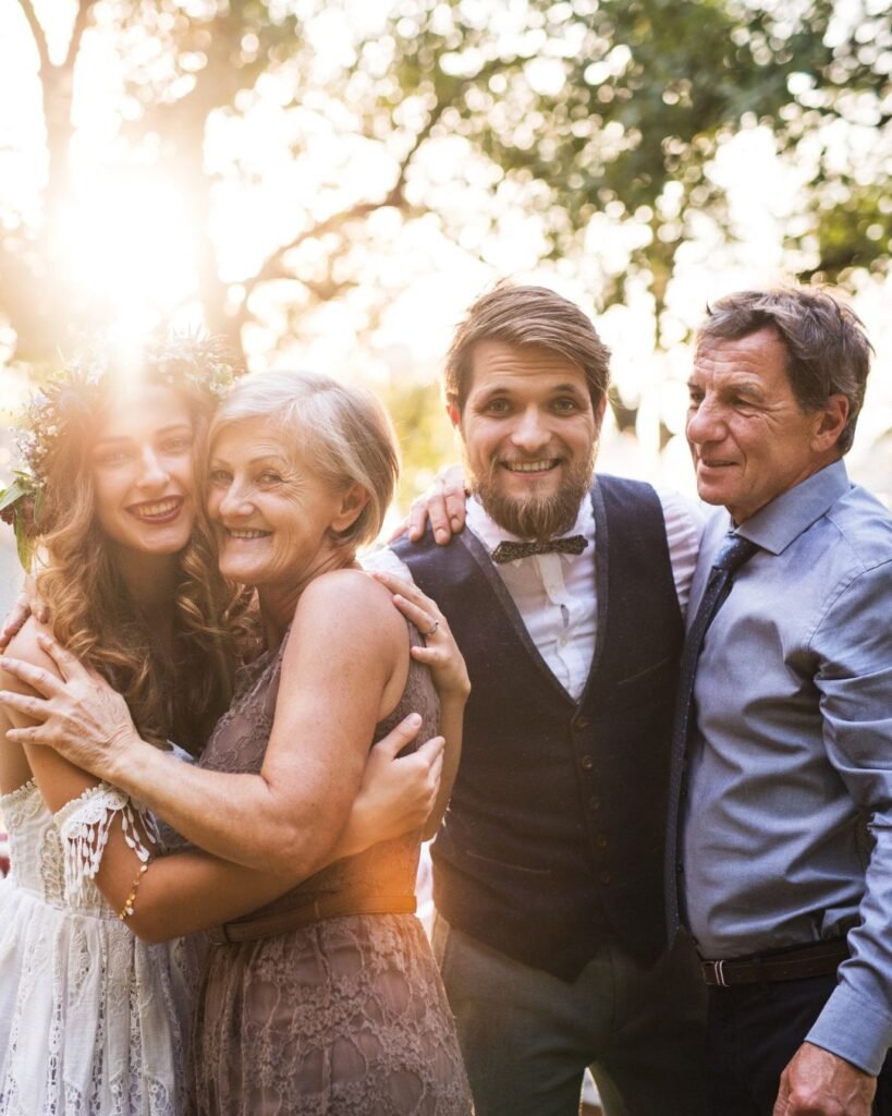 Bride and groom smiling with parents at golden hour before surprise wedding dance with parents