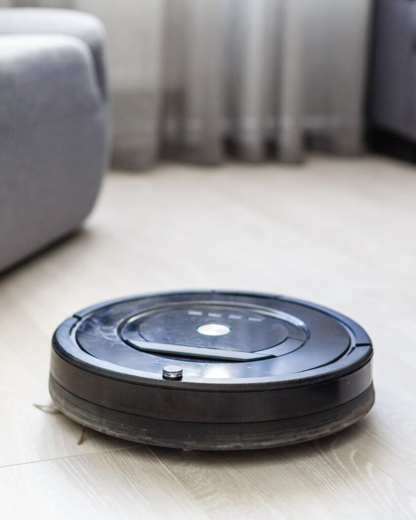 Black robot vacuum cleaning light wood floors in a modern living room