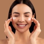 Woman applying top rated eye cream from TikTok under her eyes with a smile on her face